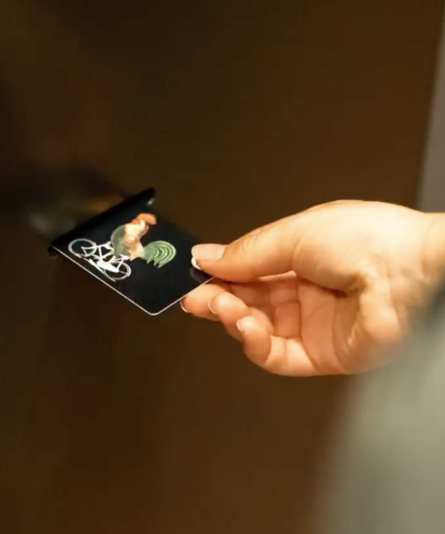 KeyCard BlackF Hand zieht eine RFID-Schlüsselkarte mit Hahn-Motiv aus der Kartenausgabe des digitalen Check-in Terminals im BLACKF Apartment.